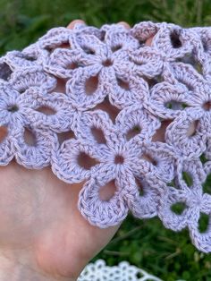 a hand is holding a crocheted object in the grass