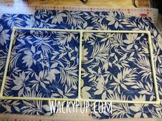 a blue and white flowered table cloth with a metal frame on the floor in front of it