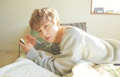 a young boy laying on top of a bed holding a toothbrush in his hand