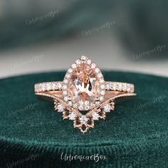 an engagement ring with a large pink diamond surrounded by small white diamonds on a green velvet box