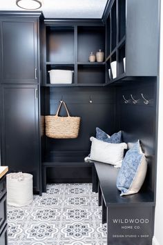 a mud room with black cabinets and white pillows on the bench in front of it