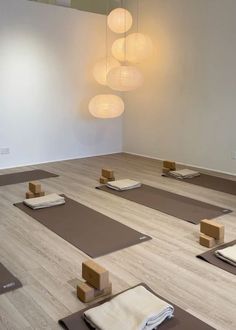 yoga mats are lined up on the floor in a room with lights hanging from the ceiling