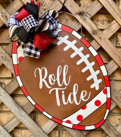 a football sign with the word roll tide painted on it and tied to a fence