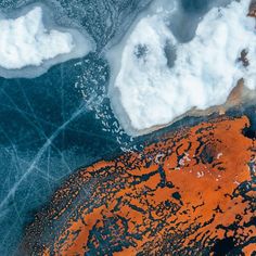 an aerial view of the ocean and land covered in orange algae, ice and snow