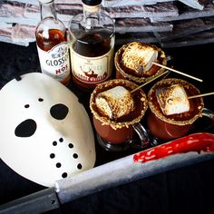 halloween treats are arranged on a table with a mask and bottle of booze in the background