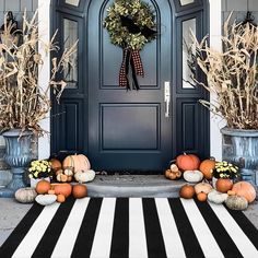 a blue front door decorated with pumpkins, corn stalks and a wreath on it