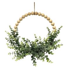 a wooden beaded wreath with green leaves and white balls hanging from it's center