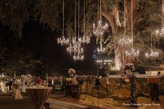 an outdoor event with chandeliers hanging from the trees