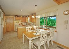 a kitchen and dining room with an open window overlooking the trees in the distance is shown