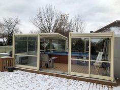 a hot tub sitting on top of a wooden deck next to a snow covered field