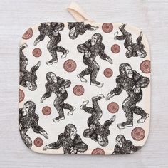 an oven mitt with monkeys on it and red circles around the pattern, sitting on top of a white surface