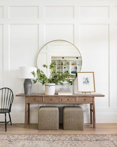 a table with two chairs and a mirror on the wall above it in a living room