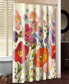 a shower curtain with colorful flowers on it in a bathroom next to a bathtub