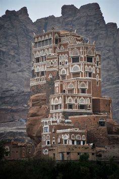 a very tall building sitting in the middle of a mountain range with many windows and balconies