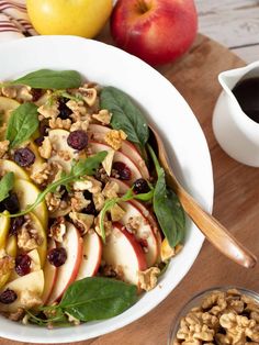 a white bowl filled with apples and walnuts next to a cup of black coffee