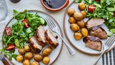 two plates with meat, potatoes and salad on them