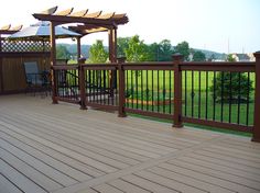 a wooden deck with chairs and an umbrella over it, overlooking a grassy area in the distance