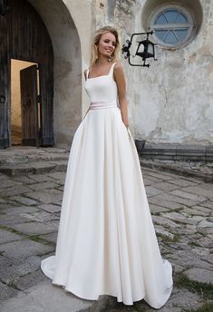 a woman standing in front of a building wearing a white dress