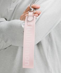 a man in grey shirt holding a pink keychain with the word ummbaloop on it