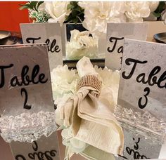 the table numbers are decorated with white flowers and silver acrylic boxes for each place setting