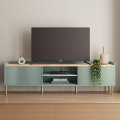 a flat screen tv sitting on top of a wooden entertainment center next to a plant