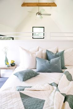 a bed with blue and white pillows in a bedroom next to a ceiling fan on the wall