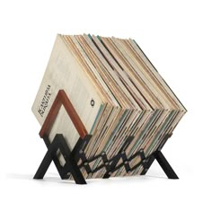 a stack of books sitting on top of a wooden stand next to an open book