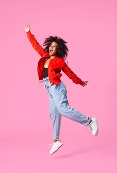 a woman is jumping in the air with her arms spread out and she's smiling