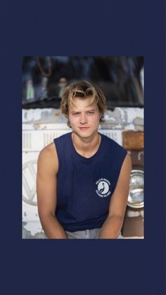 a young man sitting in front of an oven with his hands on his hips and looking at the camera