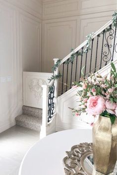 a vase filled with flowers sitting on top of a table next to a stair case