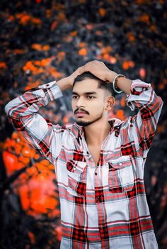 a young man is posing for the camera with his hands on his head and wearing a plaid shirt