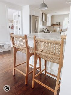 two wicker bar stools sit in the middle of a kitchen