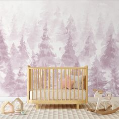 a baby crib in front of a wall with pink watercolor trees on it