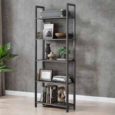 a book shelf with several books on it in front of a gray wall and potted plant