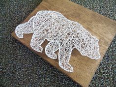 a bear made out of string sitting on top of a wooden cutting board in the middle of carpeted area