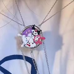 a person wearing a white shirt and holding a cell phone case with hello kitty charms on it