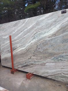 a large marble slab sitting on top of a metal stand in front of some trees