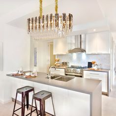 a kitchen with two bar stools and a chandelier hanging from the ceiling