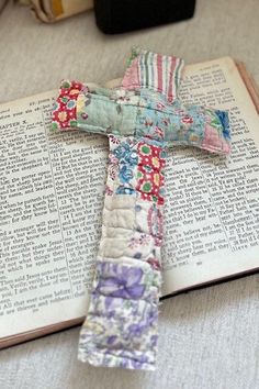 an open book with a cross made out of fabric on it sitting on a table