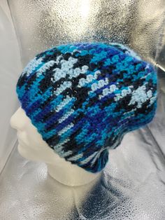 a blue and black knitted hat sitting on top of a mannequin head