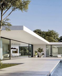 a large pool in front of a white house with glass walls and doors on the outside