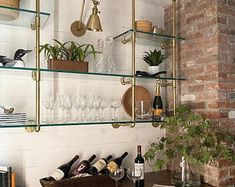 the shelves are filled with wine glasses, bottles and other items in front of a brick wall