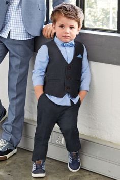 a little boy in a suit and tie standing next to a man with his arm around him