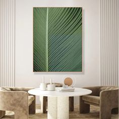 a table and chairs in a room with a large green leaf on the wall above it