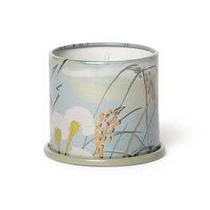 a white and blue candle holder with flowers on the inside, sitting in front of a white background