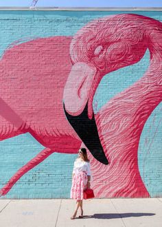 a woman standing in front of a pink flamingo wall with the caption, no instagram is complete without some stellar street art, and one of chicago's best