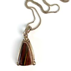 Sterling Silver Pendant With A Gorgeous Banded Agate Stone Made In Nepal. The Stone Is Bezel Set In A Triangular-Shaped Setting With A Rope Frame And Ball Beads On The Bottom Two Points Of The Triangle. The Stone Has Stripes Of Red, Orange, Brown, Blue, And Yellow. It Is Marked On The Back 925 And Has A Sticker That Reads Made In Nepal. Measurements: Length: 1.25 In / 3 Cm Width: 0.625 In / 2 Cm Condition: Very Good. The Light Patina On The Silver Could Be Polished Off. Rope Frame, Flapper Necklace, Statement Collar Necklace, Wood Bead Necklace, Crystal Bead Necklace, Banded Agate, Brown Silver, Jasper Pendant, Agate Necklace