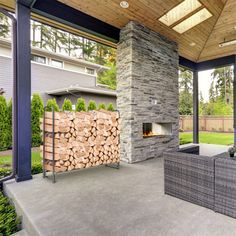 an outdoor living area with fireplace, couches and firewood stacked on top of each other