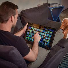 a man sitting on a couch holding an electronic device in his hand and looking at the screen