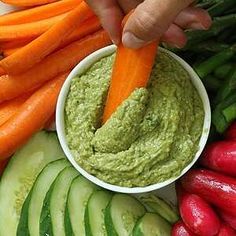 a person dipping some kind of vegetable into a bowl